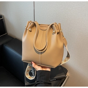 Détail du sac seau kaki montrant le cuir grainé et la bandoulière jacquard