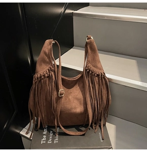 Detail shot of brown suede hobo bag featuring long decorative side tassels and gold hardware