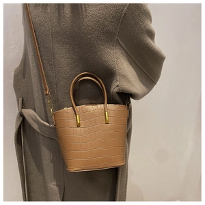 Detail of khaki crocodile pattern bucket bag paired with a brown wool coat on model