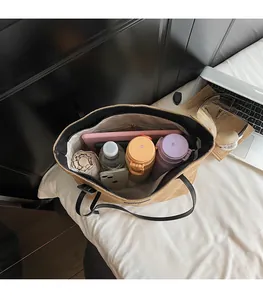 Top view of spacious beige quilted tote bag interior holding a laptop and essentials