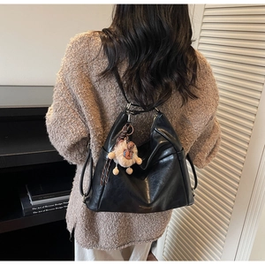 Close-up of black leather hobo bag with a cute plush lion charm and metal hardware details