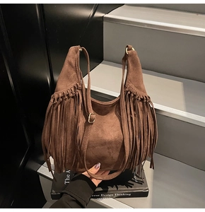 Detail of a brown suede hobo bag with long fringes and an adjustable metal buckle strap