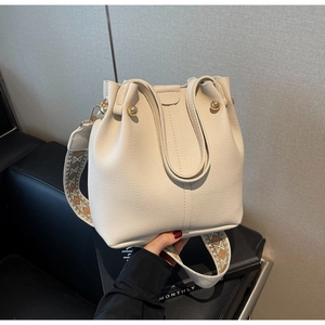 Détail du sac seau crème avec texture litchi et large bandoulière géométrique