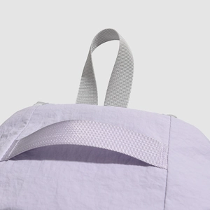 Detail view of the light purple backpack showing the woven gray handle and fabric texture