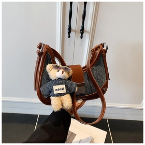 Detail of half-moon shoulder bag in brown leather and denim with plush bear charm