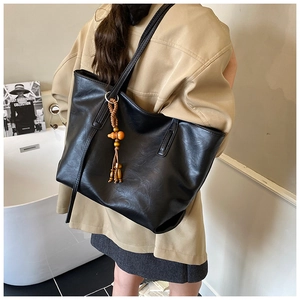 Borsa tote nera minimalista con nappa in legno mostrata in scena lifestyle