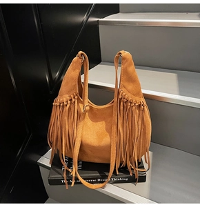 Close-up of retro brown suede crescent bag featuring long decorative side tassels