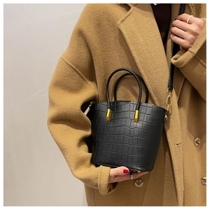 Close-up of black crocodile-embossed bucket bag with golden hardware and top handle