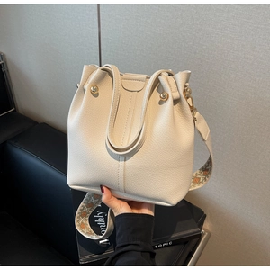 Gros plan du sac seau crème en cuir litchi avec bandoulière jacquard ethnique