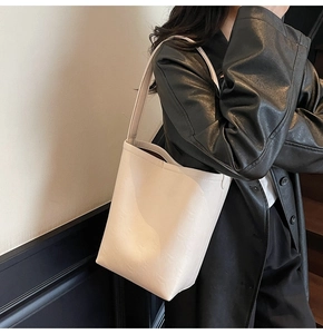 Detail of off-white tote bag showing smooth faux leather texture and large capacity