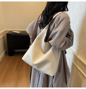Close-up of white woven tote bag hobo style with smooth synthetic leather texture