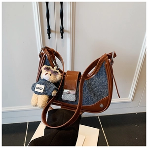 Detail of blue denim and brown leather saddle bag with a silver metal buckle closure