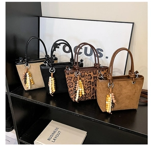Multiple color options of suede bucket bags with beaded tassels on a display stand