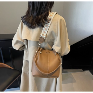 Sac seau marron avec rivets dorés et une large bandoulière tissée colorée