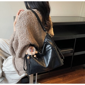 Detail of black PU leather tote bag with soft texture and a cute brown plush bear charm