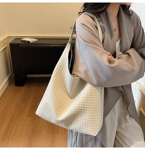 Close-up of beige woven leather hobo bag with textured finish worn by a model