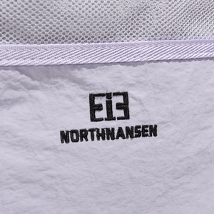 Detail of lavender fabric with Northnansen logo embroidery and grey mesh texture