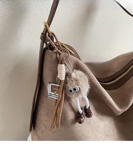 Gros plan d'un pendentif en peluche marron avec de longues jambes sur un sac en daim