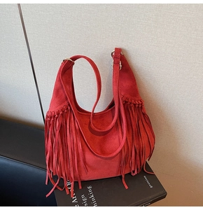 Close-up of red faux suede tote bag featuring bohemian long fringe and metal ring details
