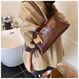 Detail shot of vintage dark brown faux leather shoulder bag with metallic logo and tassel