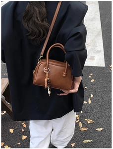 Detail of vintage brown oil wax leather bowling bag with bead pendant on street background