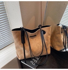 Detail of beige quilted faux suede tote bag with black straps and brand plate