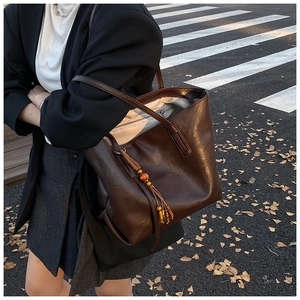 Dettaglio borsa tote marrone in pelle PU con nappa di perline e sfondo urbano autunnale