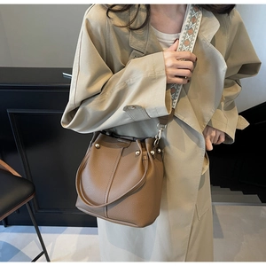 Gros plan du sac seau en cuir avec sangle jacquard et détails de clous dorés