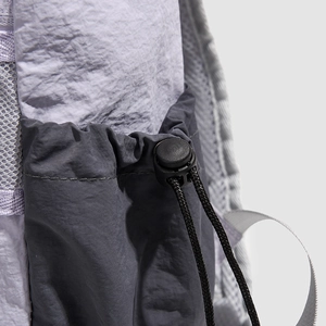 Detail of the nylon backpack showing side pocket drawstring toggle and mesh fabric texture