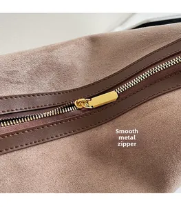 Gros plan sur la fermeture éclair dorée et la texture du sac cabas en daim marron