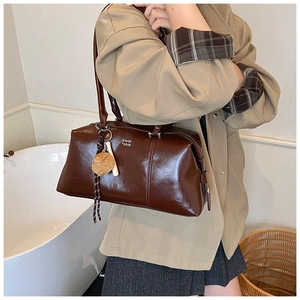 Close-up of vintage dark brown faux leather Boston bag with a cute bear charm accessory