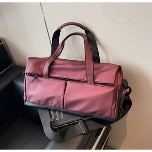 Détail du sac de sport bordeaux en tissu haute densité avec sangle sur un canapé en cuir