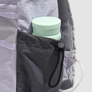 Detail view of backpack side pocket with drawstring closure and a green water bottle inside