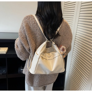 Detail view of cream white tote bag with a cute brown lion plush charm on side pocket