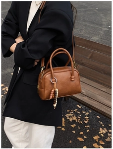 Outdoor street shot of a vintage brown leather Boston bag with wooden bead charm detail