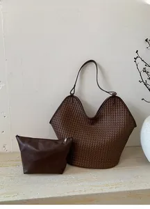 Detail of woven bucket bag and small leather pouch on stone surface in autumn setting