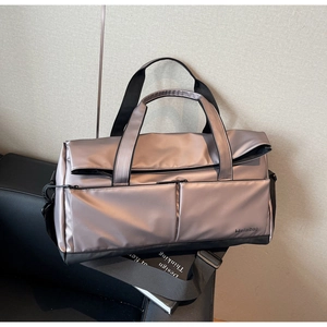 Détail d'un sac de sport champagne brillant sur un canapé en cuir noir élégant