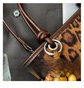 Macro detail of leopard print bucket bag featuring brown leather trim and retro beaded charm