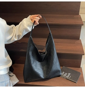 Close-up of black woven leather Hobo bag with intricate geometric texture and handle