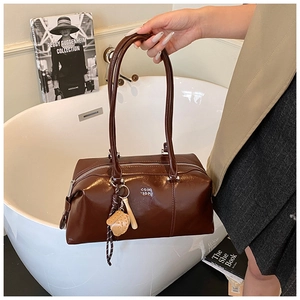 Close-up of deep brown oil wax leather Boston bag with charm and logo detail