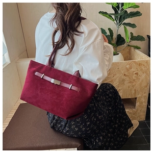 Detail view of burgundy faux suede tote bag featuring silver metal buckle and strap