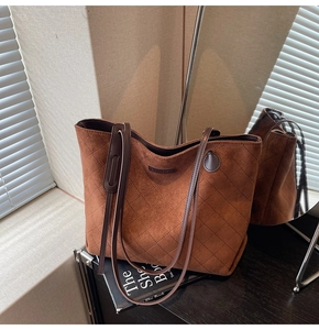 Macro view of brown quilted suede tote bag showcasing fine stitching and leather texture