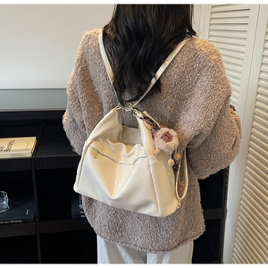 Detail of white glossy backpack with soft folds and cute lion plush charm accessory