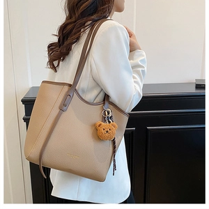 Detail of khaki pebbled leather tote bag with brown trim and cute bear charm ornament