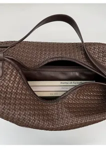 Detail of dark brown woven bucket bag showing spacious interior and zipper pocket