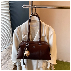 Detail of dark brown vintage Boston bag with glossy leather and baseball glove charm