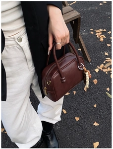 Close-up of vintage brown leather Boston bag with decorative wooden beads and zipper detail