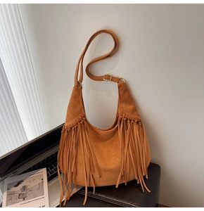 Detailed close-up of dark brown suede hobo bag featuring long stylish fringe tassels