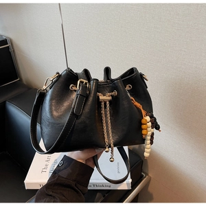 Detailed view of black matte leather bucket bag with gold chain and colorful bead decor