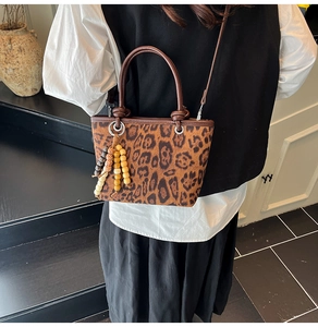 Close-up of leopard print bucket bag with wooden bead tassel and leather handles
